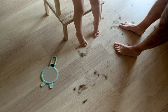 Child and parent standing near hair clippings on floor
