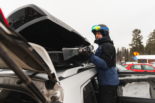 Skier Loading Equipment into Car Roof Cargo Box in Winter