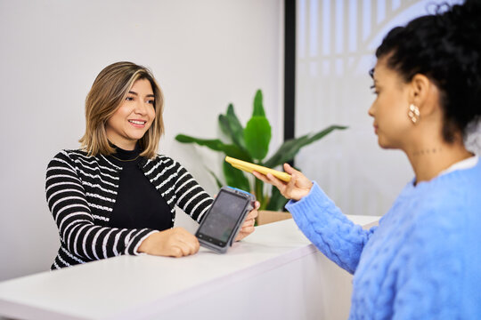 Customer making contactless payment using smartphone at reception