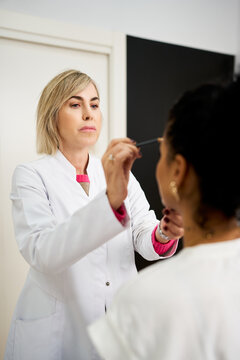 Cosmetologist performing eyebrow microblading on client in salon