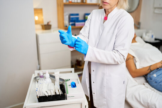 Professional aesthetician wearing blue gloves preparing