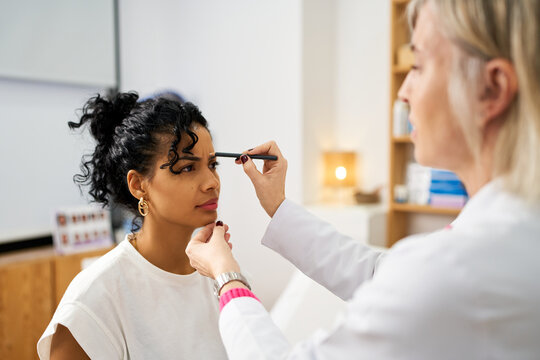Woman getting eyebrow shaping treatment in beauty salon