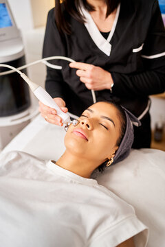 Woman receiving facial microcurrent treatment in beauty salon