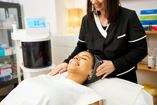 Woman smiling receiving head massage in beauty salon