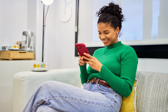 Woman smiling using smartphone waiting in beauty salon