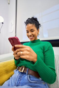 Woman smiling and texting on smartphone in salon