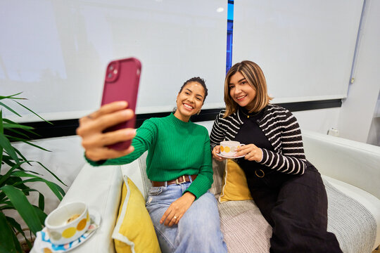 Friends taking selfie enjoying coffee at salon