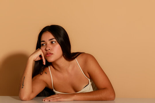 Young Woman Posing With Hand on Face by Simple Background Indoors