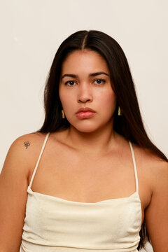 Woman With Long Hair Poses Against a Plain Background Indoors