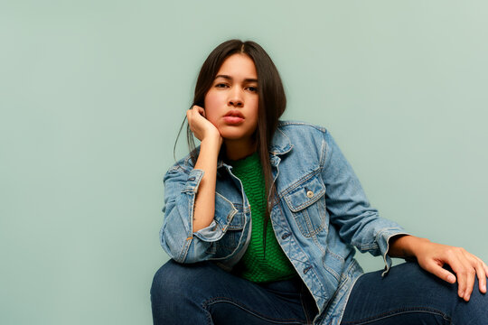 Young Woman Sits Against Blue Wall 