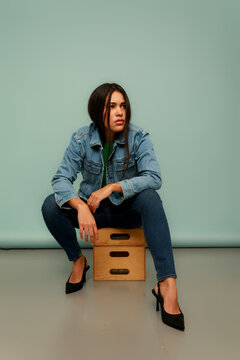 A Woman is Seated on a Small Box With Her Legs Bent