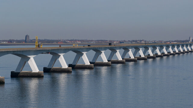 Aerial view of Zeeland Bridge with its iconic white X-shaped concrete pillars spanning across the Oosterschelde under a clear blue sky Zierikzee, Zeeland, Netherlands.