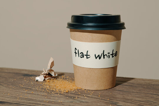 a takeaway cup labeled flat white on a table