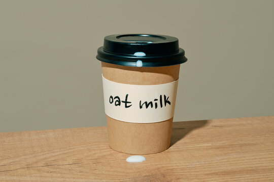 a paper cup labeled oat milk with milk dripping