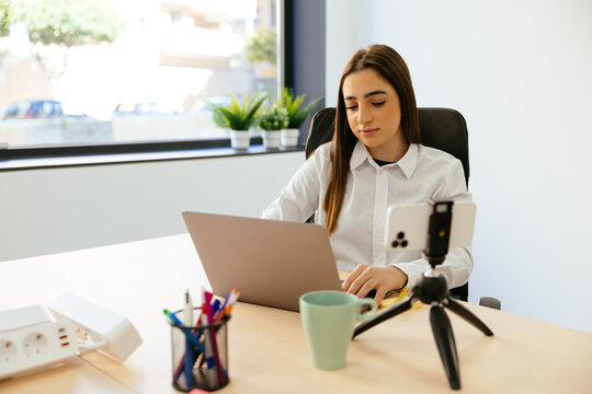 Woman working on laptop and smartphone tripod