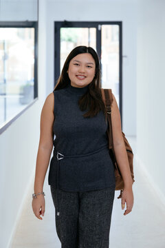 Asian student smiling backpack walking university hallway