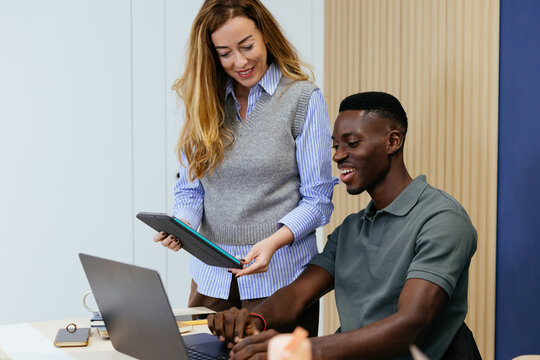 Diverse business team collaborating using digital tablet and laptop