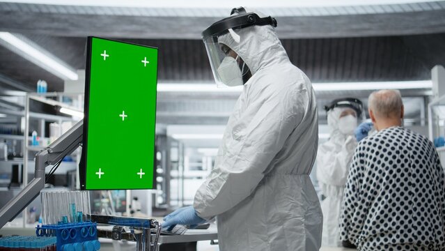 Vertical green screen next to black medic in hazmat suit observing contagious epidemic in lab, examining patient with serious symptoms. Preventing global disaster and health crisis. Camera A.