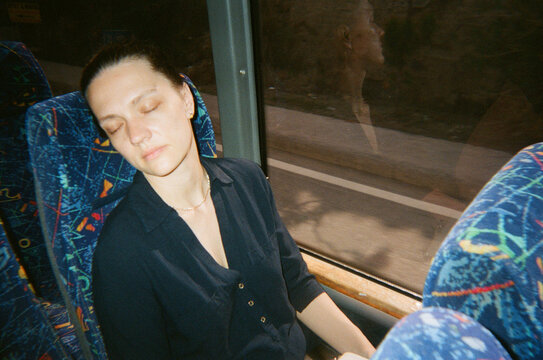 Woman Resting on a Bus During a Journey 