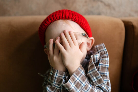 The child covers his face with his hands