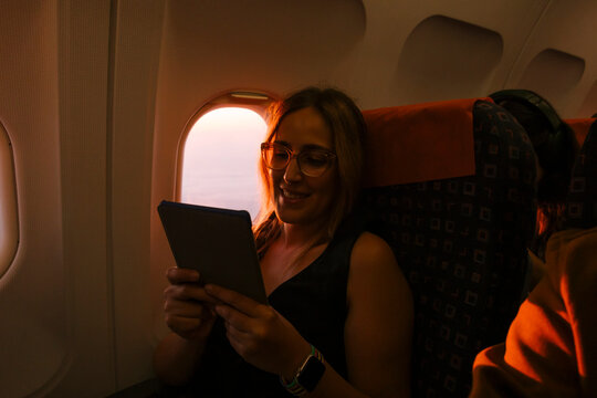 Woman Reading E-reader by Airplane Window 