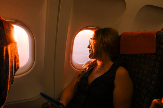 Passenger Gazes out of Airplane Window 
