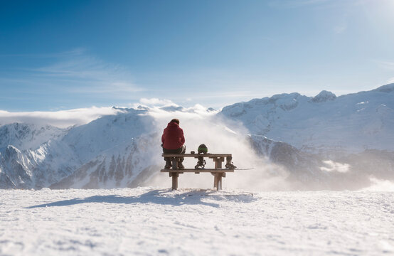 Snowboarder Resting on a Bench Contemplating Mountain View