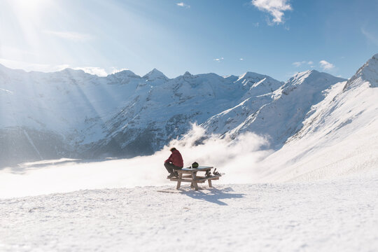 Snowboarder resting on table with scenic winter mountains