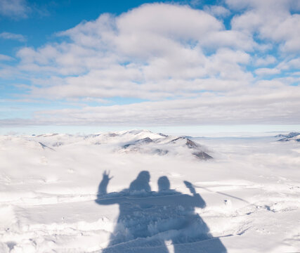 Shadow of Two Hikers on a Snowy Mountain Summit