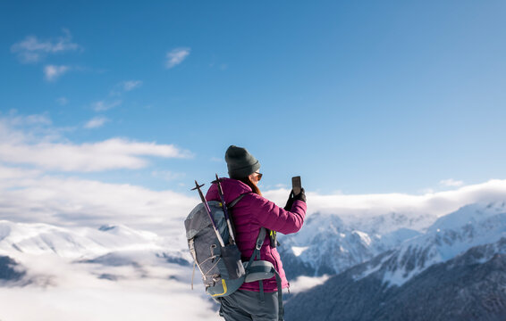 Hiker Photographing Snowy Mountain Panorama