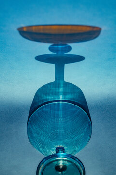 Glasses and plate create shadows on blue surface at sunset