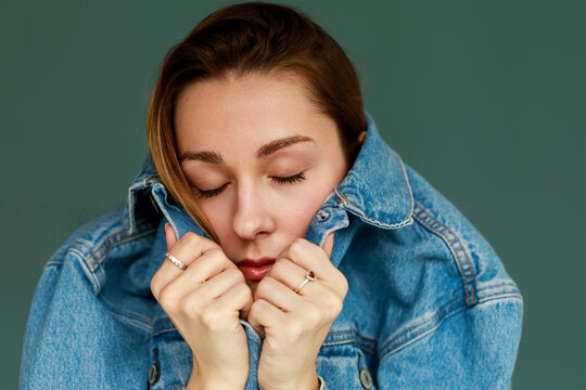 Woman Closing Her Denim Jacket With a Calm Expression 