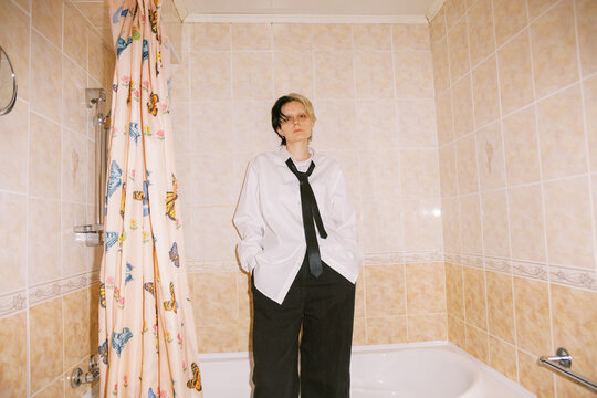 Person Stands in a Bathroom Wearing a White Shirt and Black Tie
