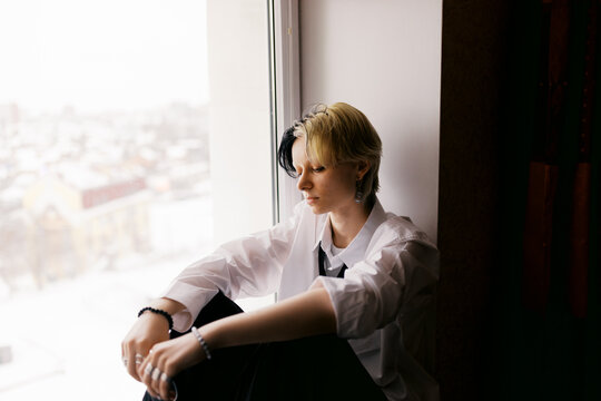 Woman Sits by Window and Looks Outside at City View
