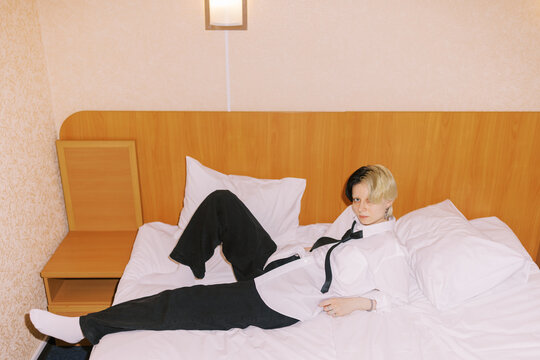 Person Laying on Bed in Room With Minimal Furniture and White Sheets