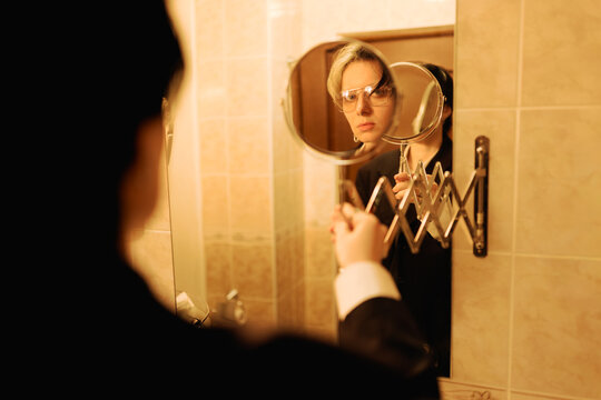 Person Looks at Self in Mirror While Holding a Small Mirror in Hand