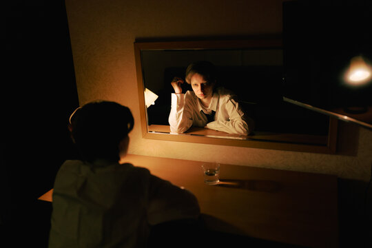 Person Gazes Into Mirror in Dimly Lit Room at Night