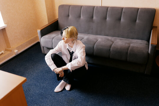 Person Sitting on Floor Near Sofa in Room With Simple Decor