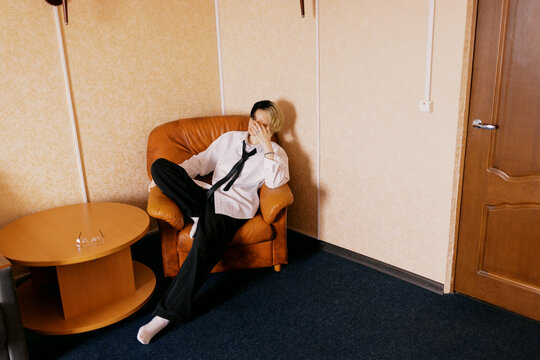 Person Sitting on a Chair in a Room With Plain Walls and Carpet