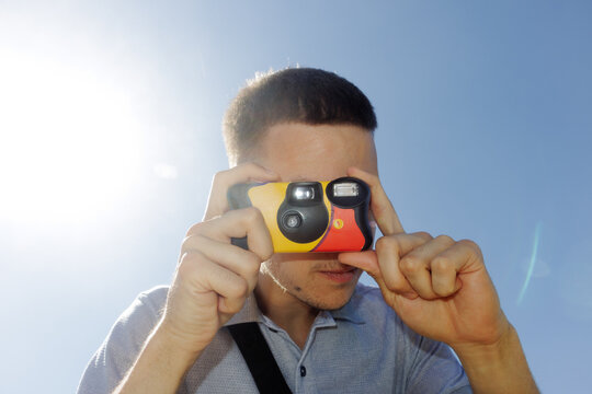 A young man takes a picture with a disposable film camera