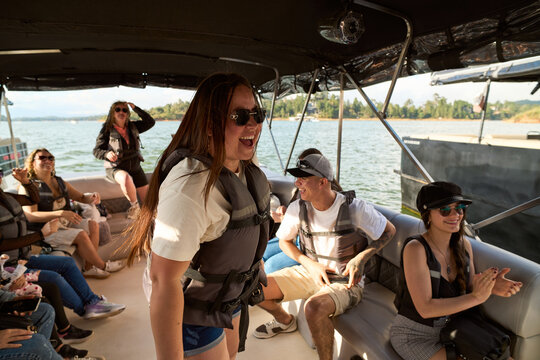 Group of friends enjoying fun summer boat trip on lake