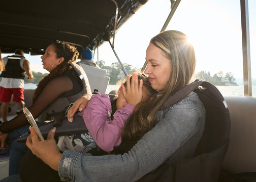 Mother comforting daughter while boating on lake