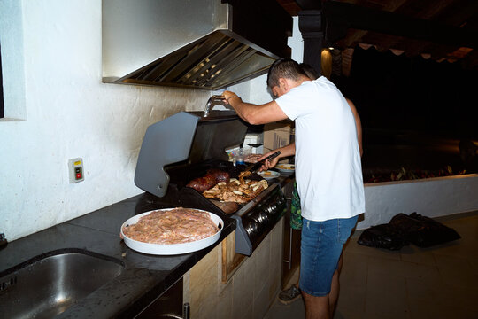 Person grilling meat on outdoor barbecue at night