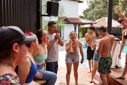 Happy friends laughing enjoying summer pool party outdoors