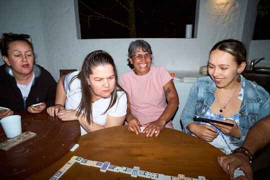 Women friends playing dominoes game together at home