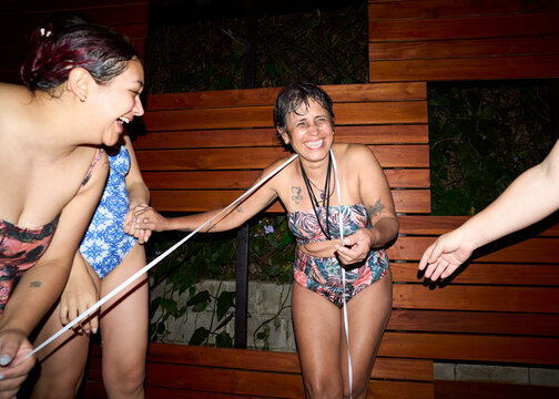 Happy women friends enjoying night pool party together