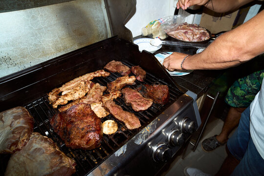 Person grilling meat and steak on barbecue at party