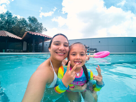 Mother and daughter enjoying fun summer swimming pool vacation