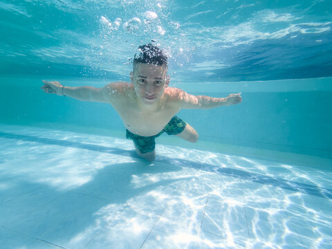 Young man swimming underwater in pool enjoying freedom