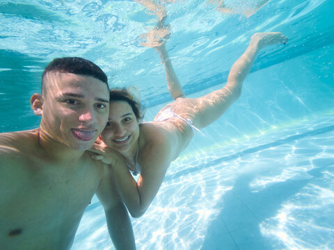 Young couple taking underwater selfie in swimming pool